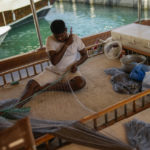 
              A man sews a fishing net, to be sold in Souq Waqif market, on a wooden boat harboured at Doha bay, in Doha, Qatar, Sunday, Nov. 20, 2022. Pearl fishing drove Qatar’s economy until the 1930s. The dangerous, seasonal trade employed nearly all the former British protectorate’s young men and many slaves. But the market collapsed in the early 20th century with the Japanese invention of artificial pearls. (AP Photo/Francisco Seco)
            