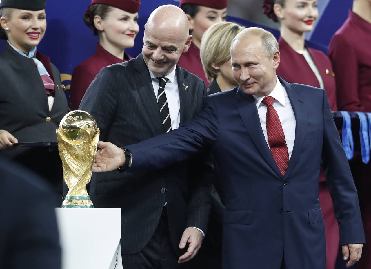 FILE - Russian President Vladimir Putin touches the World Cup trophy as FIFA President Gianni Infan...