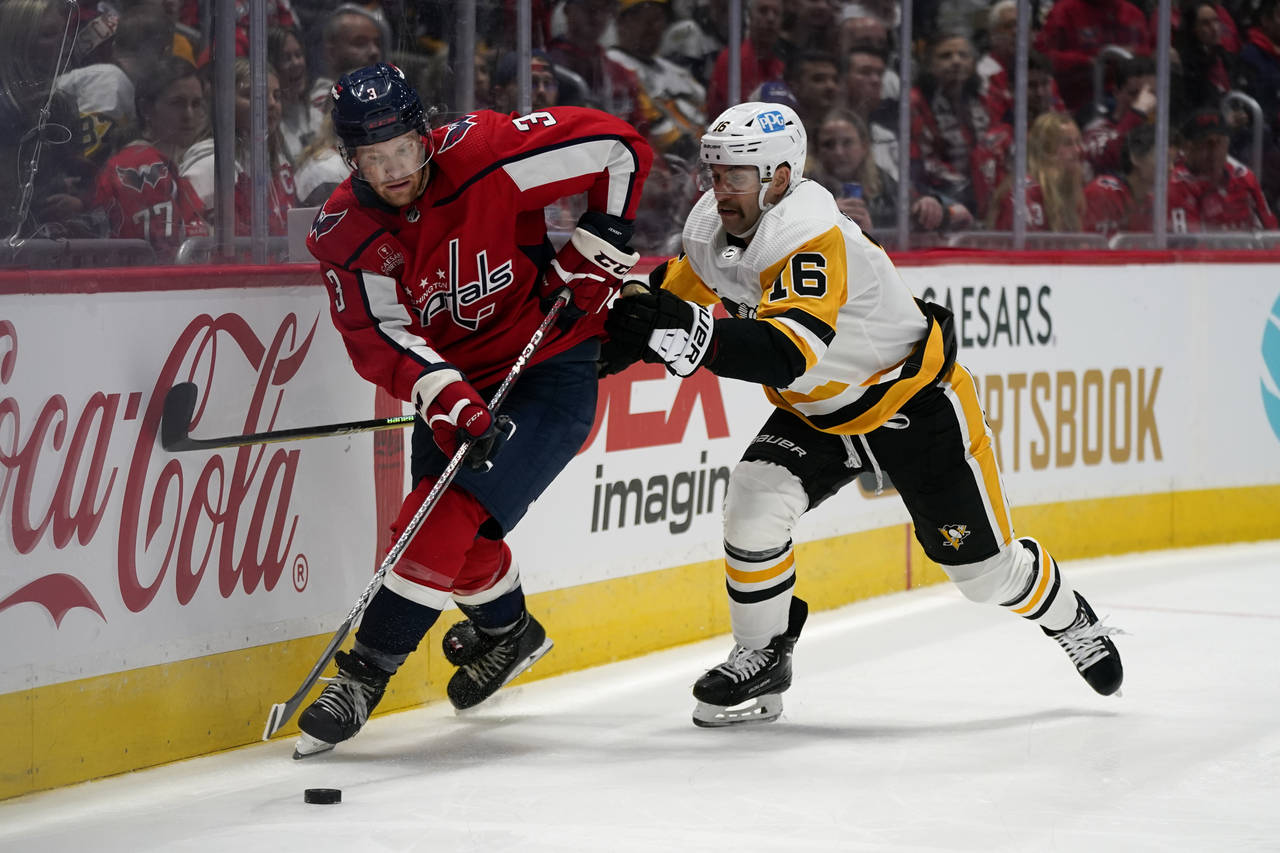 Washington Capitals defenseman Nick Jensen, left, skates with the puck as he is pressured by Pittsb...