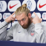 
              Tim Ream of the United States points to his hair bun after calling himself and teammate Walker Zimmerman "the bun brothers" during a press conference before a team practice at Al Gharafa SC Stadium, in Doha, Qatar, Sunday, Nov. 27, 2022. (AP Photo/Ashley Landis)
            