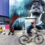 
              A mural painting of late soccer star Diego Maradona is seen as people pass by, during the second anniversary of his death at West Bay, in Doha, Qatar, Friday, Nov. 25, 2022. (AP Photo/Jorge Saenz)
            