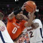 
              Illinois' Terrence Shannon Jr. (0) drives into Virginia's Reece Beekman (2) during the first half of an NCAA college basketball game Sunday, Nov. 20, 2022, in Las Vegas. (AP Photo/John Locher)
            