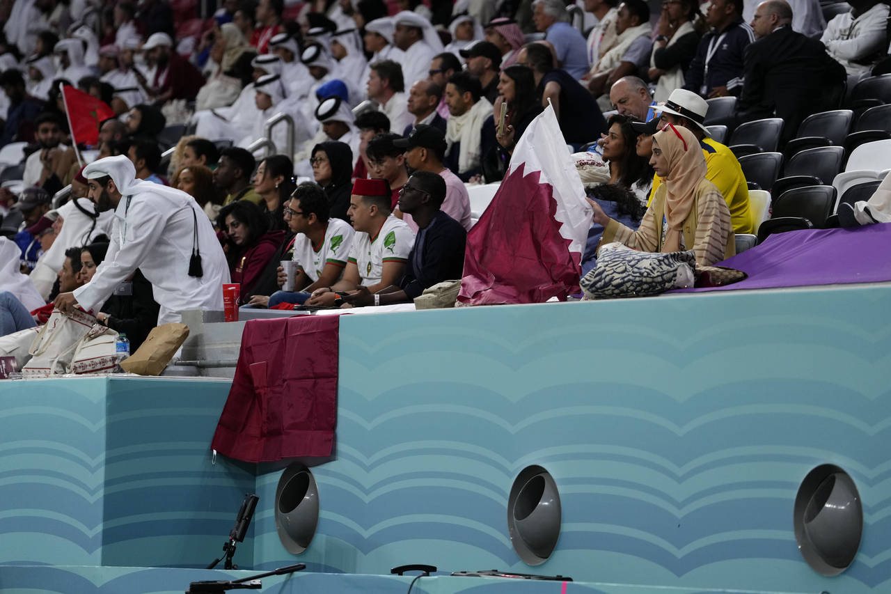Fans sit on the stands above air conditioning ventilators during a World Cup group A soccer match b...