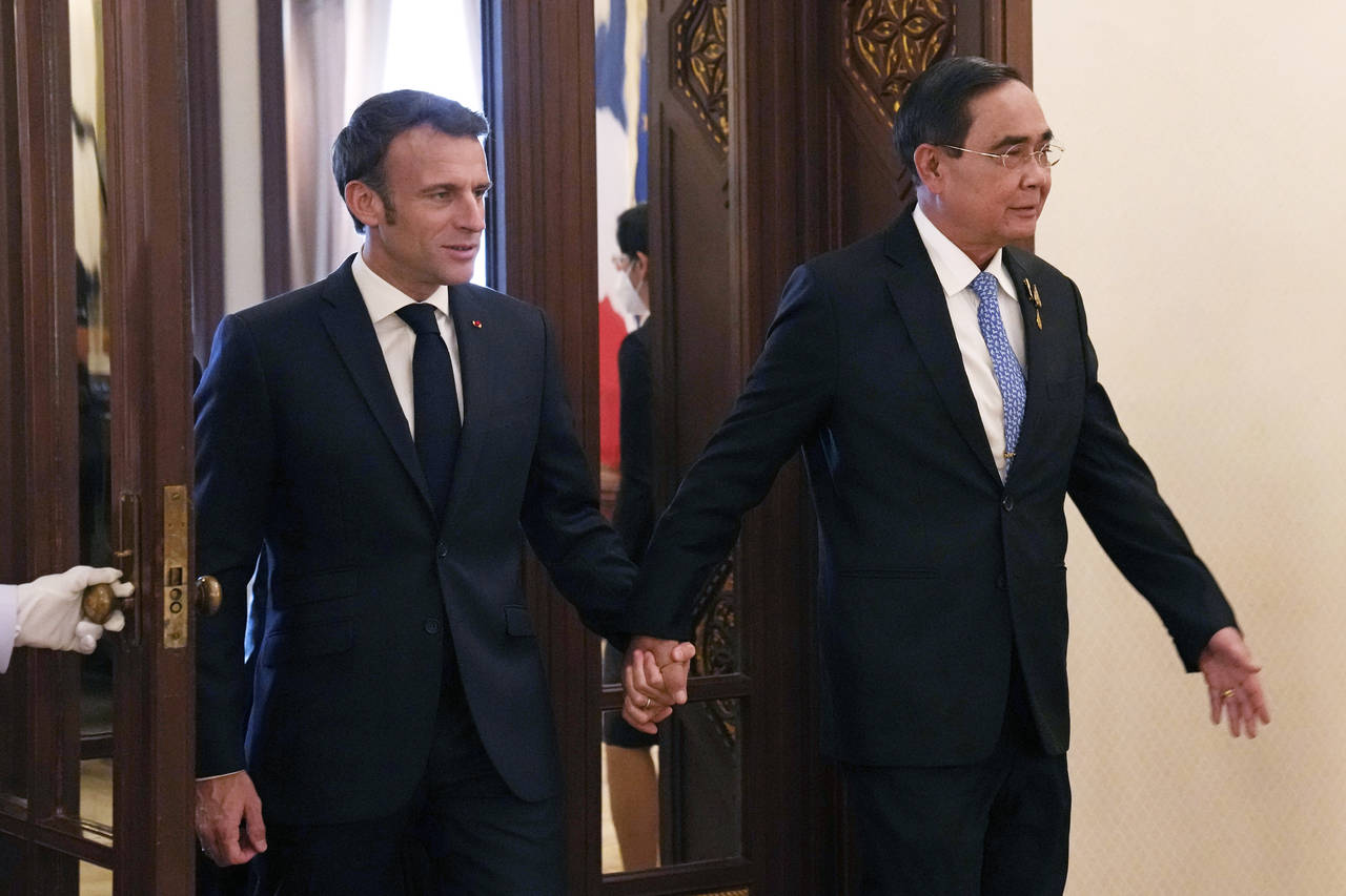 Thailand's Prime Minister Prayuth Chan-ocha, right, walks hand in hand with French President Emmanu...