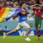 
              A pitch invader runs across the field with a rainbow flag during the World Cup group H soccer match between Portugal and Uruguay, at the Lusail Stadium in Lusail, Qatar, Monday, Nov. 28, 2022. (AP Photo/Abbie Parr)
            