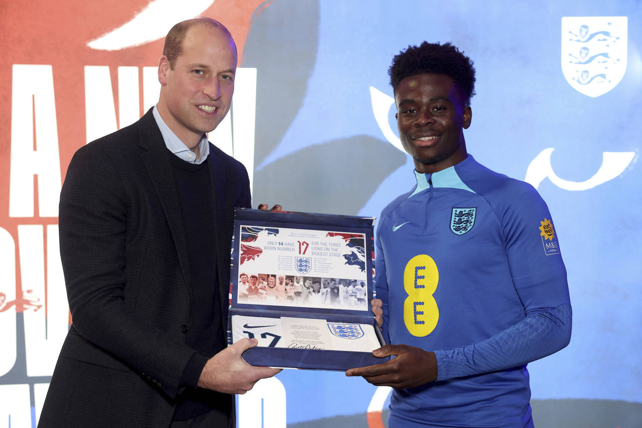 Britain's Prince William, left, presents the England shirt to midfielder Bukayo Saka during his vis...