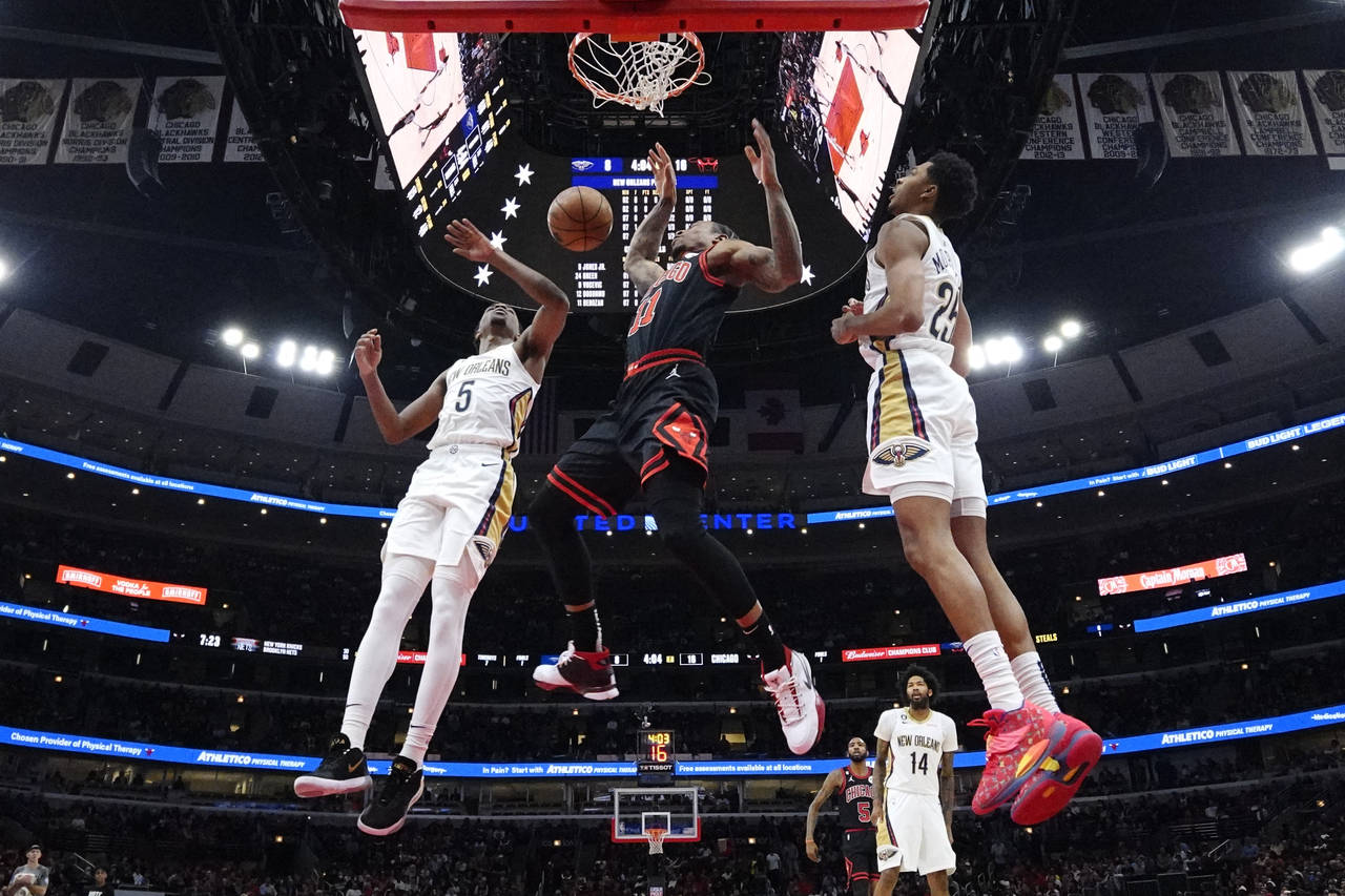 Chicago Bulls forward DeMar DeRozan, center, scores a basket between New Orleans Pelicans forward H...