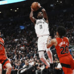 
              Brooklyn Nets guard Kyrie Irving (11) scores over Toronto Raptors guard Jeff Dowtin Jr. (20) as Raptors forward Juancho Hernangomez (41) watches during the second half of an NBA basketball game Wednesday, Nov. 23, 2022, in Toronto. (Chris Young/The Canadian Press via AP)
            