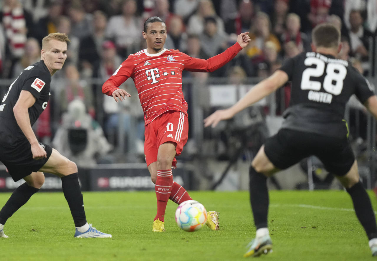 Bayern's Leroy Sane, centre, controls the ball ahead of Freiburg's Matthias Ginter during the Germa...