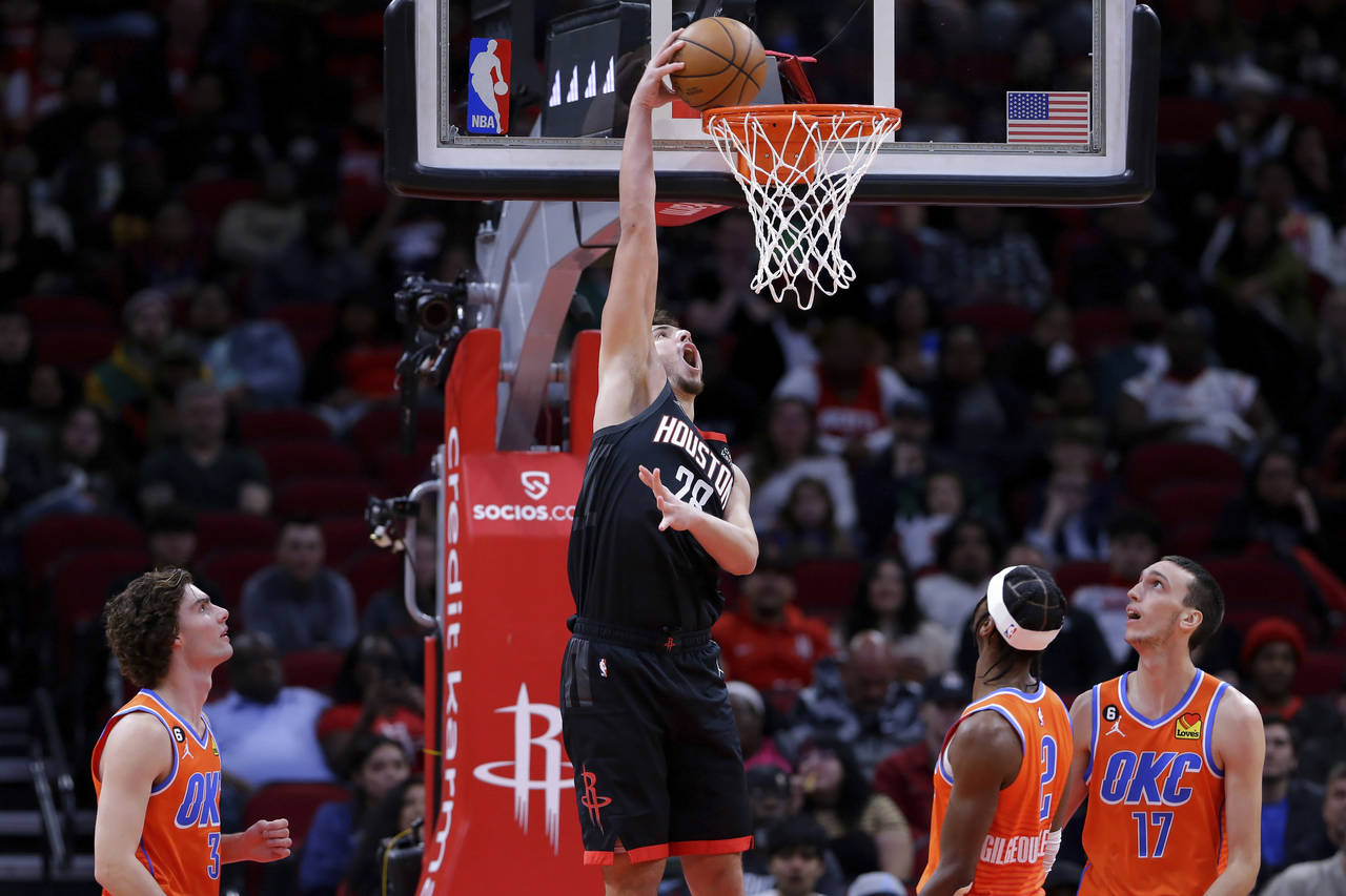 Houston Rockets center Alperen Sengun dunks over Oklahoma City Thunder guards Josh Giddey (3) and S...