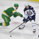 
              Winnipeg Jets center Mark Scheifele (55) controls the puck in front of Minnesota Wild defenseman Jake Middleton (5) during the first period of an NHL hockey game Wednesday, Nov. 23, 2022, in St. Paul, Minn. (AP Photo/Andy Clayton-King)
            