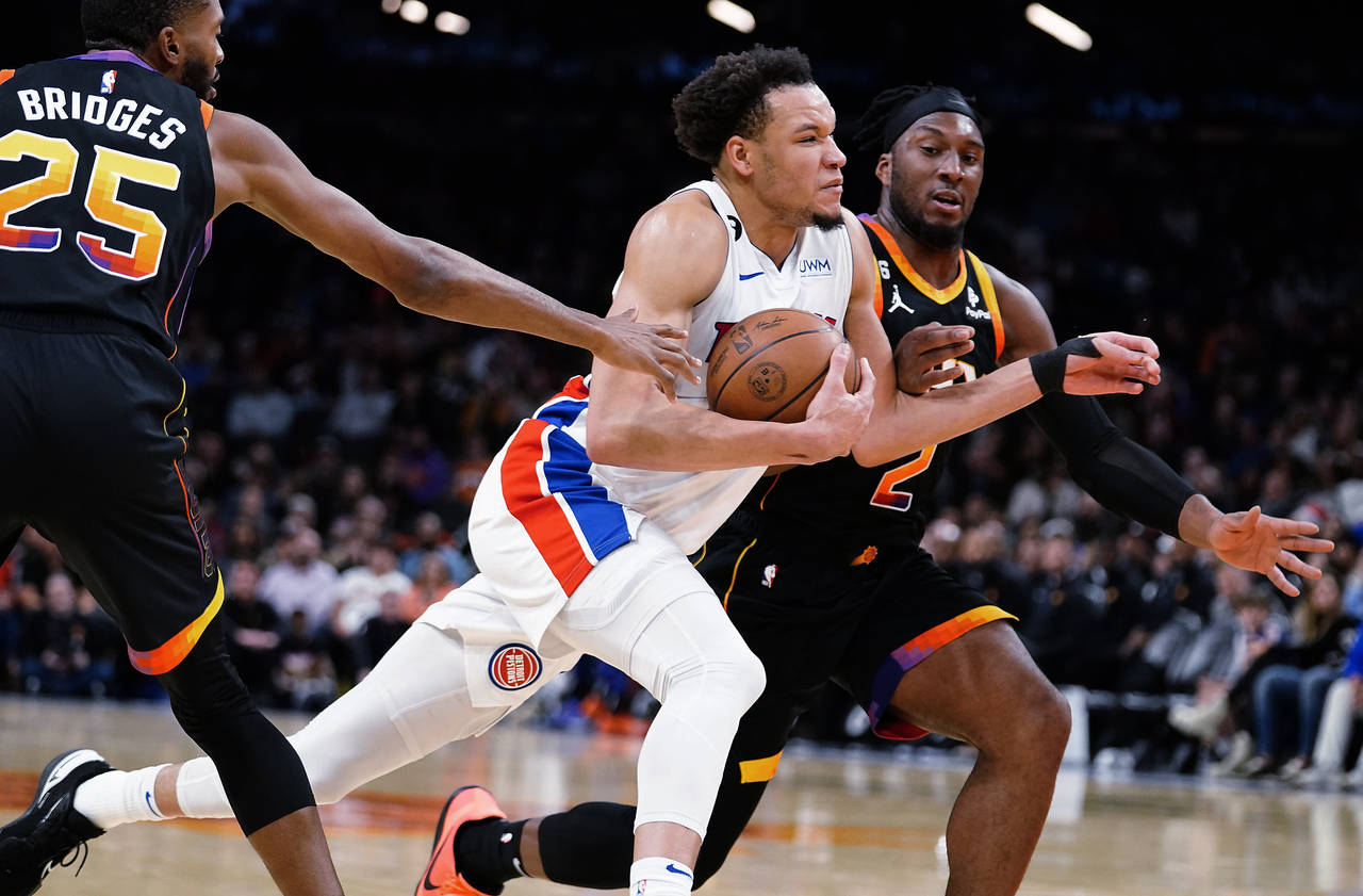 Detroit Pistons' Kevin Knox II (20) drives to the basket between Phoenix Suns' Mikal Bridges (25) a...