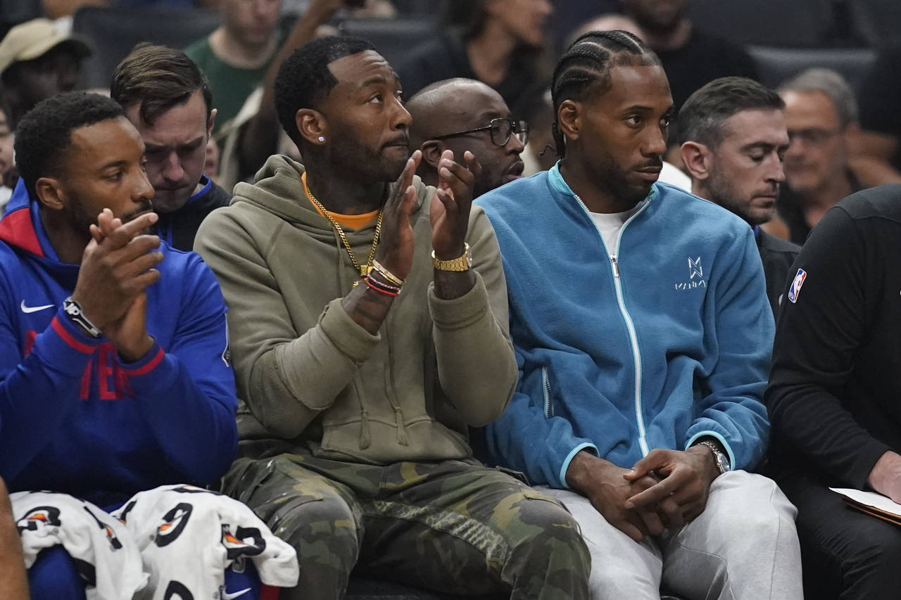 LA Clippers guard John Wall, center, and forward Kawhi Leonard, right, sit on the bench during the ...