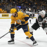 
              Nashville Predators' Dante Fabbro (57) moves the puck ahead of Arizona Coyotes' Christian Fischer (36) in the first period of an NHL hockey game Monday, Nov. 21, 2022, in Nashville, Tenn. (AP Photo/Mark Humphrey)
            