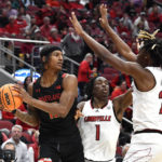 
              Maryland forward Julian Reese looks for help form the defense of Louisville guard Mike James (1) and forward Kamari Lands during the first half of an NCAA college basketball game in Louisville, Ky., Tuesday, Nov. 29, 2022. (AP Photo/Timothy D. Easley)
            