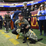 
              Washington Commanders quarterback Taylor Heinicke (4) poses with a dog as he meets fans and members of the military before the start of an NFL football game against the Minnesota Vikings, Sunday, Nov. 6, 2022, in Landover, Md. (AP Photo/Nick Wass)
            