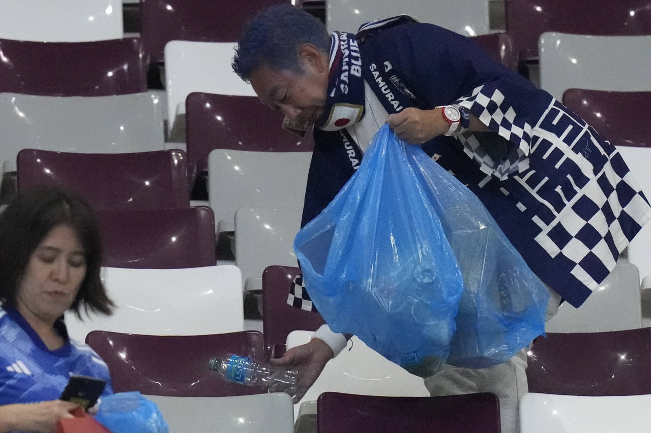 Japan supporters clean the stands at the end of the World Cup group E soccer match between Germany ...