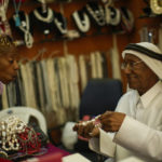 
              A former pearl diver Saad Ismail talks to a client in his pearl shop in Souq Waqif market in Doha, Qatar, Saturday, Nov. 19, 2022. Pearl fishing drove Qatar’s economy until the 1930s. The dangerous, seasonal trade employed nearly all the former British protectorate’s young men and many slaves. But the market collapsed in the early 20th century with the Japanese invention of artificial pearls. (AP Photo/Francisco Seco)
            