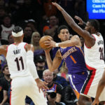 
              Phoenix Suns guard Devin Booker (1) looks to pass under pressure from Portland Trail Blazers forward Justise Winslow (26) during the first half of an NBA basketball game, Saturday, Nov. 5, 2022, in Phoenix. (AP Photo/Matt York)
            