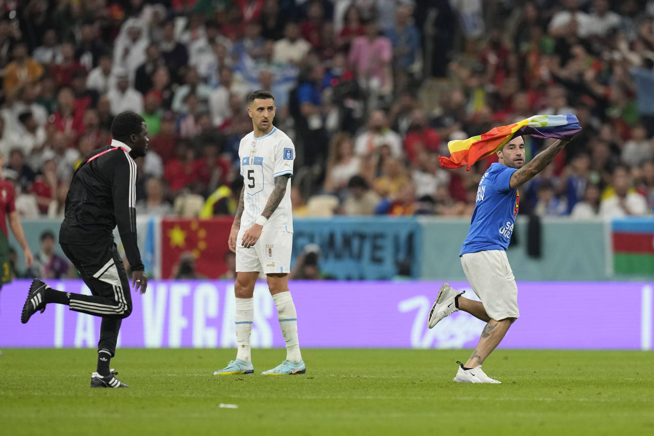 A pitch invader runs onto the pitch with a rainbow flag during the World Cup group H soccer match b...