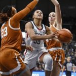 
              Connecticut's Azzi Fudd, center, splits the defense of Texas' Aaliyah Moore, left, and Taylor Jones, right, during the first half of an NCAA college basketball game, Monday, Nov. 14, 2022, in Storrs, Conn. (AP Photo/Jessica Hill)
            
