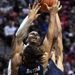 
              San Diego State guard Micah Parrish, top, shoots over the defense of Cal State Fullerton forwards Lathaniel Bastian (14) and Vincent Lee, right, during the first half of an NCAA college basketball game Monday, Nov. 7, 2022, in San Diego. (AP Photo/Denis Poroy)
            