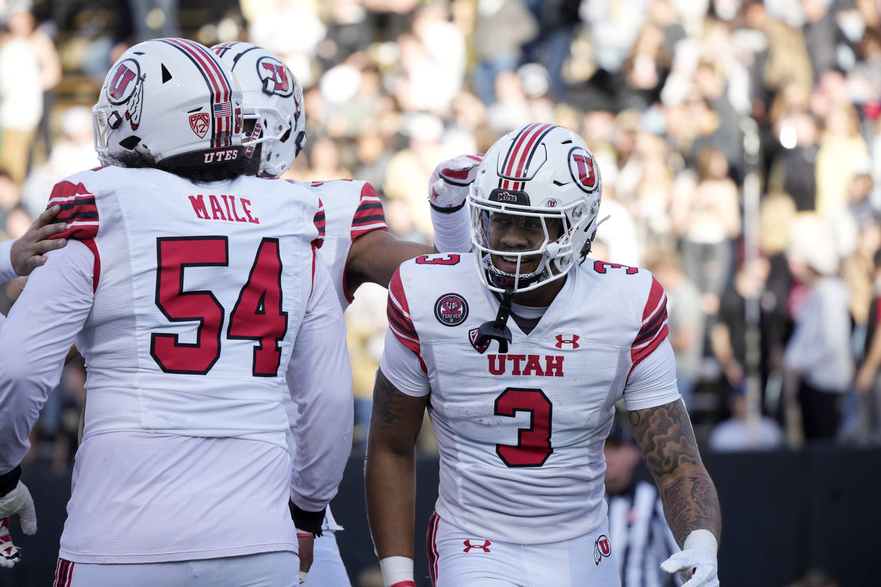 Utah quarterback Ja'Quinden Jackson, right, is congratulated by offensive lineman Paul Maile after ...