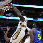 
              New Orleans Pelicans forward Zion Williamson (1) slam dunks over Golden State Warriors center Kevon Looney (5) in the first half of an NBA basketball game in New Orleans, Monday, Nov. 21, 2022. (AP Photo/Gerald Herbert)
            