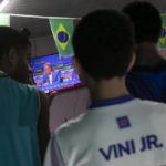 
              Students watch Brazil coach Tite announce his list of players for the 2022 Soccer World Cup in Qatar, at the Paulo Freire municipal school where player Vinicius Jr. studied, in Sao Goncalo, Rio de Janeiro state, Brazil, Monday, Nov. 7, 2022. Four years ago teenager Vinicius Jr. took his first medal from a professional soccer tournament home, a place where drug gangs and vigilantes fight for control and children dribble past garbage on the streets. Today, Vinicius is a key figure on Brazil’s World Cup team. (AP Photo/Bruna Prado)
            