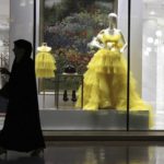 
              FILE - A woman passes by fashion outfit at the Al Hazm luxury mall, in Doha, Qatar, Wednesday, April 24, 2019. The foreign fans descending on Doha for the 2022 FIFA World Cup will find a country where women work, hold public office and cruise in their supercars along the city's palm-lined corniche. (AP Photo/Kamran Jebreili, File)
            