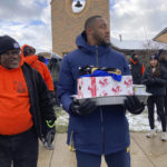 
              Michigan linebacker Nikhai Hill-Green holds a tray containing a turkey, vegetables and other items during a giveaway event outside a school in Ypsilanti, Mich., on Sunday, Nov. 20, 2022. Hill-Green took part in the charitable effort, which was spearheaded by his friend and Michigan teammate Blake Corum, less than a week before their third-ranked Wolverines play No. 2 Ohio State. (AP Photo/Mike Householder)
            