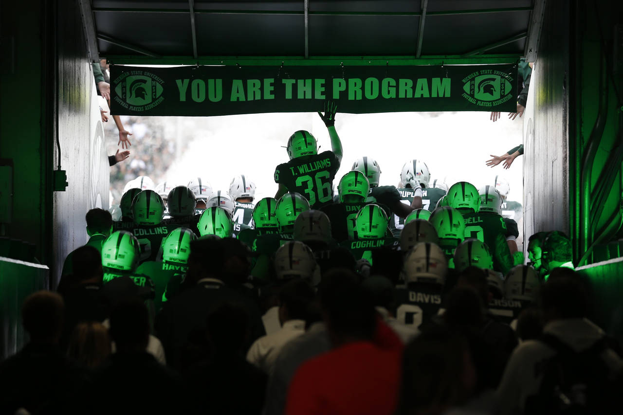 FILE - Michigan State players run through the tunnel to take the field before an NCAA college footb...