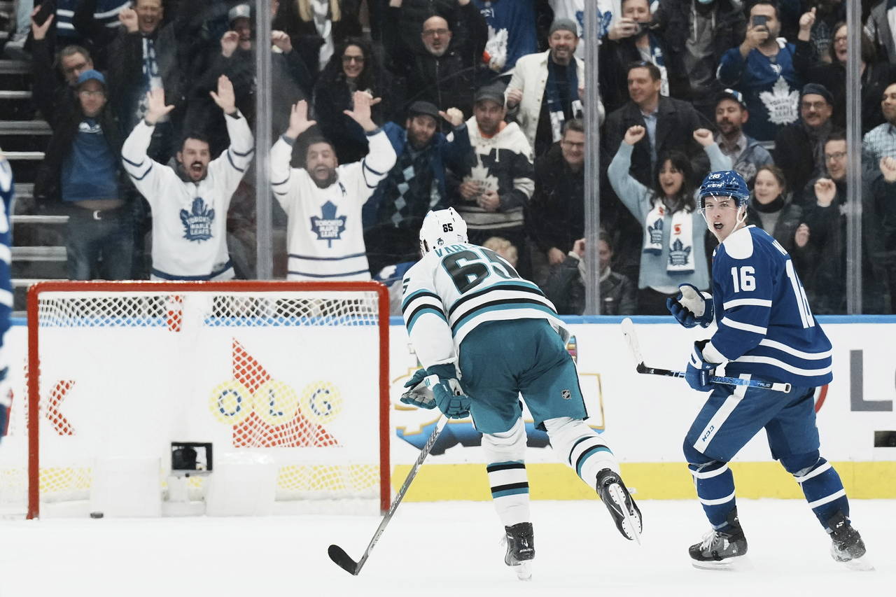 Toronto Maple Leafs' Mitchell Marner, right, turns to celebrate after scoring an empty-net goal aga...