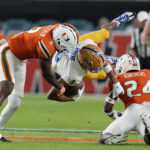 
              Pittsburgh wide receiver Jared Wayne (5) is tackled by Miami cornerback Tyrique Stevenson (2) and safety Kamren Kinchens (24) during the first half of an NCAA college football game Saturday, Nov. 26, 2022, in Miami Gardens, Fla. (AP Photo/Lynne Sladky)
            