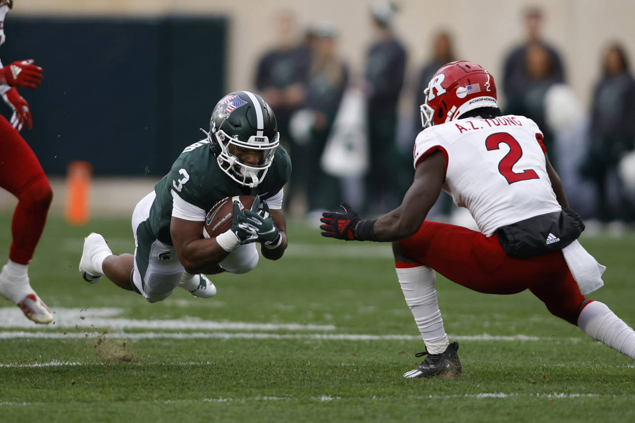 Michigan State running back Jarek Broussard, left, dives for yardage against Rutgers' Avery Young (...