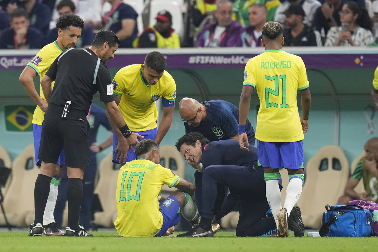 Brazil's Neymar, bottom, is treated by members of his team during the World Cup group G soccer matc...