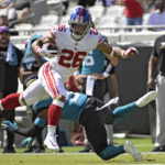 
              New York Giants running back Saquon Barkley (26) leaps over Jacksonville Jaguars safety Andre Cisco (5) on a rush during the first half of an NFL football game Sunday, Oct. 23, 2022, in Jacksonville, Fla. (AP Photo/Phelan M. Ebenhack)
            