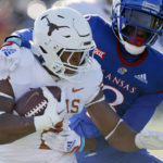 
              Texas running back Roschon Johnson, left, is stopped by Kansas cornerback Ra'Mello Dotson (3) during the first quarter of an NCAA college football game, Saturday, Nov. 19, 2022, in Lawrence, Kan. (AP Photo/Colin E. Braley)
            