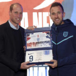 
              Britain's Prince William, left, presents the England shirt to forward Harry Kane during his visit to the England soccer team at St George's Park ahead of the team's trip to the World Cup in Qatar, in Burton upon Trent, England, Monday, Nov. 14, 2022. Prince William joined a private team meeting and presented the players with their shirt numbers on Monday evening. (Eddie Keogh/The FA via AP)
            