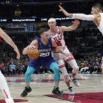 
              Charlotte Hornets forward Gordon Hayward (20) drives as Chicago Bulls guard Goran Dragic, left, center Nikola Vucevic, right, and guard Alex Caruso, rear, defend during the first half of an NBA basketball game in Chicago, Wednesday, Nov. 2, 2022. (AP Photo/Nam Y. Huh)
            