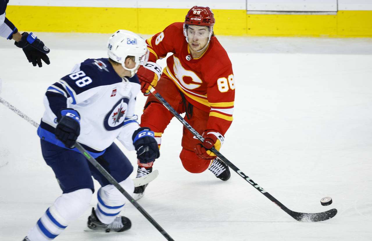Winnipeg Jets defenceman Nate Schmidt, left, checks Calgary Flames forward Andrew Mangiapane during...