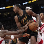 
              Cleveland Cavaliers' Evan Mobley, center, looks to pass the ball after being crowded by the Toronto Raptors defense during first-half NBA basketball game action in Toronto, Monday, Nov. 28, 2022. (Chris Young/The Canadian Press via AP)
            