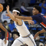 
              UCLA guard Jaime Jaquez Jr., left, reaches for the ball next to Pepperdine forward Jevon Porter (14) during the first half of an NCAA college basketball game Wednesday, Nov. 23, 2022, in Los Angeles. (AP Photo/Marcio Jose Sanchez)
            
