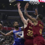 
              Los Angeles Clippers guard Paul George (13) passes against Cleveland Cavaliers forward Dean Wade (32) and forward Evan Mobley (4) during the first half of an NBA basketball game in Los Angeles, Monday, Nov. 7, 2022. (AP Photo/Ashley Landis)
            
