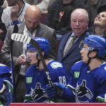 
              Vancouver Canucks head coach Bruce Boudreau, back right, and assistant coach Mike Yeo stand on the bench behind players Nils Aman (88), of Sweden, and Andrei Kuzmenko (96), of Russia, during the third period of an NHL hockey game against the Carolina Hurricanes in Vancouver, British Columbia,  Monday, Oct. 24, 2022. (Darryl Dyck/The Canadian Press via AP
            