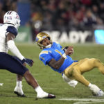 
              UCLA quarterback Dorian Thompson-Robinson, right, slips as he runs the ball while under pressure from Arizona safety Christian Young during the first half of an NCAA college football game Saturday, Nov. 12, 2022, in Pasadena, Calif. (AP Photo/Mark J. Terrill)
            