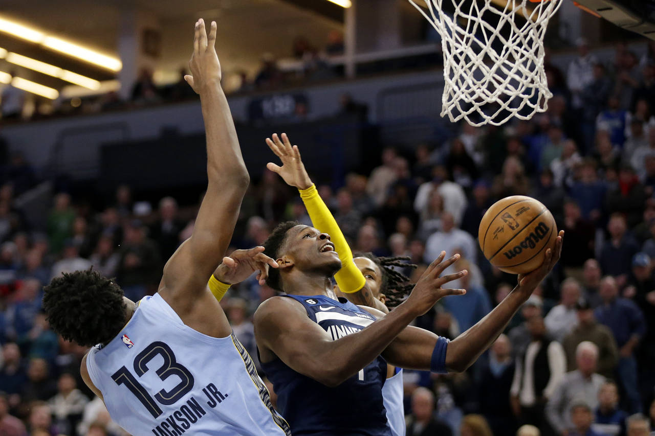 Timberwolves guard Anthony Edwards (1) shoots on Memphis Grizzlies guard Ja Morant, right, and Memp...