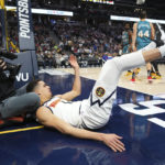
              Denver Nuggets forward Michael Porter Jr. falls into a cameraman while playing against the Detroit Pistons during the third quarter of an NBA basketball game, Tuesday, Nov. 22, 2022, in Denver. (AP Photo/Jack Dempsey)
            