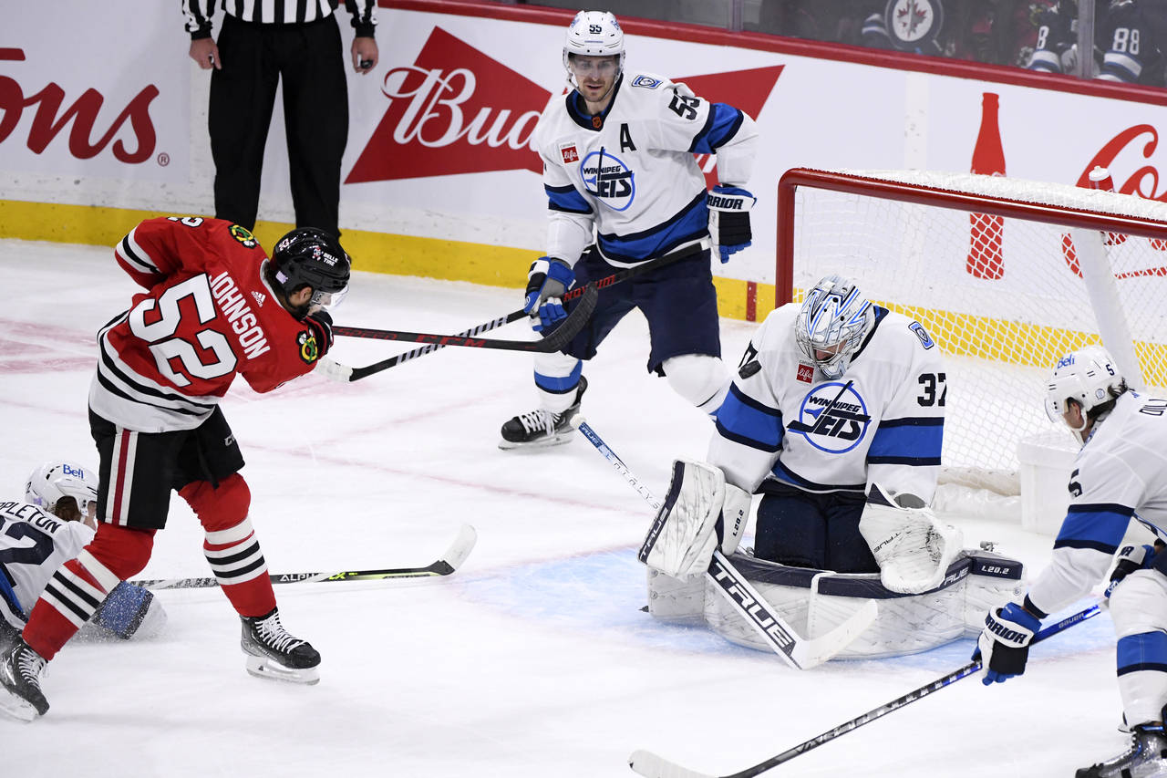 Winnipeg Jets goaltender Connor Hellebuyck (37) makes a save on a shot by Chicago Blackhawks' Reese...