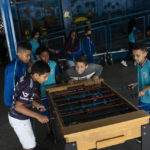 
              Students play a game of foosball before the announcement of the list of Brazil national team players for the 2022 Soccer World Cup in Qatar, at the Paulo Freire municipal school where the player Vinicius Jr. studied, in Sao Goncalo, Rio de Janeiro state, Brazil, Monday, Nov. 7, 2022. Four years ago teenager Vinicius Jr. took his first medal from a professional soccer tournament home, a place where drug gangs and vigilantes fight for control and children dribble past garbage on the streets. Today, Vinicius is a key figure on Brazil’s World Cup team. (AP Photo/Bruna Prado)
            